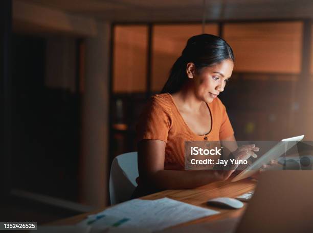 Shot Of An Attractive Young Businesswoman Sitting Alone In The Office At Night And Using A Digital Tablet Stock Photo - Download Image Now