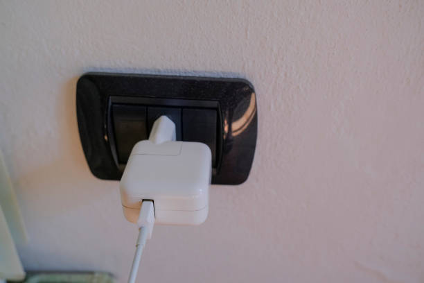 istock White charger in black electric plug on a wall close-up. Charging smartphone. Technologies 1352428681