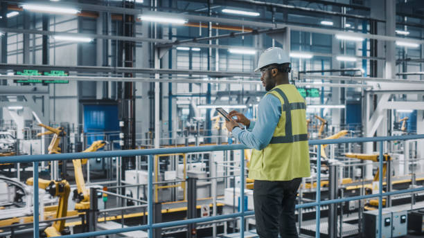 istock African American Car Factory Engineer in High Visibility Vest Using Tablet Computer. Automotive Industrial Manufacturing Facility Working on Vehicle Production on Automated Technology Assembly Plant. 1352428738