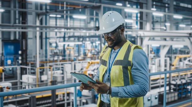 istock African American Car Factory Engineer in High Visibility Vest Using Tablet Computer. Automotive Industrial Manufacturing Facility Working on Vehicle Production on Automated Technology Assembly Plant. 1352428871