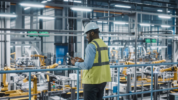 istock African American Car Factory Engineer in High Visibility Vest Using Tablet Computer. Automotive Industrial Manufacturing Facility Working on Vehicle Production on Automated Technology Assembly Plant. 1352428885