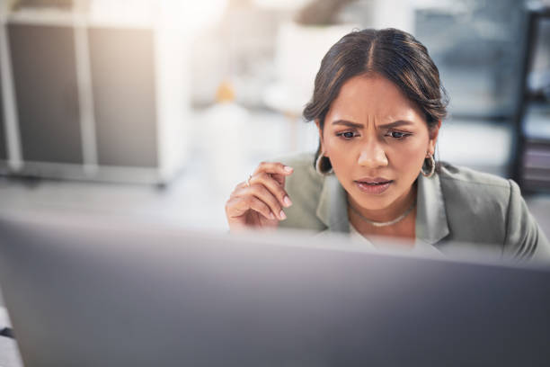 Shot of an attractive young businesswoman sitting in the office and looking confused while using her computer Wait, what?! Confusion stock pictures, royalty-free photos & images