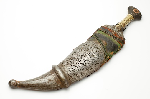 Several traditional ethnographic knives and daggers: a karud or choora from Afghanistan, Arabian jambiyas, a Sudanese arm dagger, a Kurdish dagger, and a Middle Eastern shibrya. All were photographed on a light, plain background.