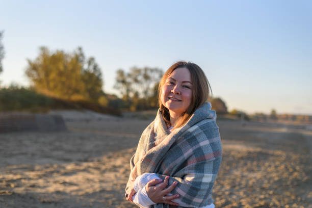 istock Woman with big wool scarf walking on beach 1352432185