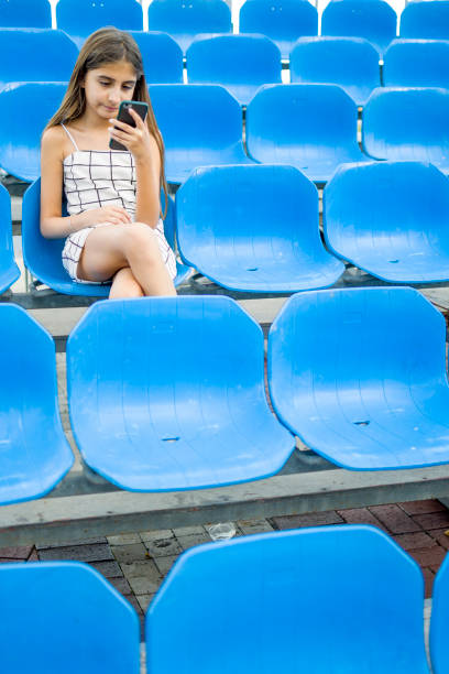 istock Littel girl using mobile phone front blue tribune 1352433293