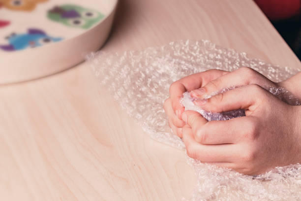 istock Stress concept. Woman's hands popping bubbles of a bubble paper on a table. 1352433711