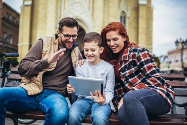 istock Family sitting on bench, relaxing using gadget, browsing internet. 1352434693