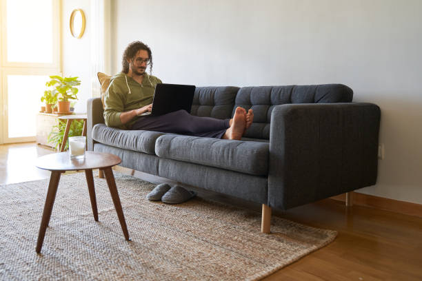 istock Wide shot of young man using laptop on the sofa 1352436305