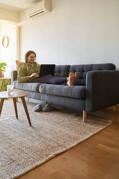 istock Vertical shot of young man using laptop on the sofa 1352436421