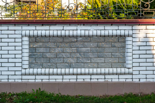 Decorative modern fence of white brick with pillars and patterns.
