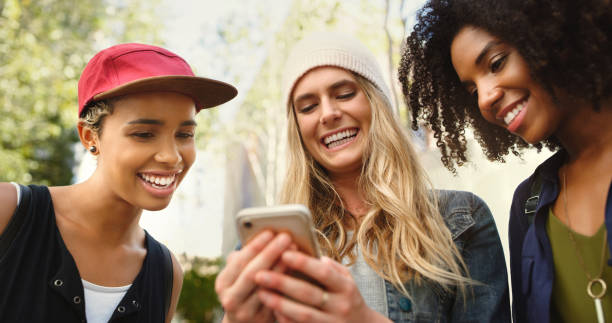 istock Shot of friends looking at something on a cellphone while standing outside 1352437846