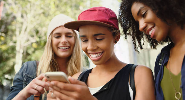 istock Shot of friends looking at something on a cellphone while standing outside 1352437851