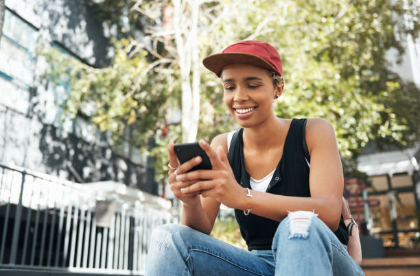 istock Shot of a young woman using her cellphone while sitting outside 1352437891