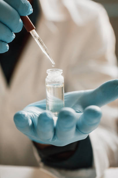 CBD hemp oil, Scientist holding bottle of Cannabis oil against Marijuana plant. Herbal Treatment, Alternative Medicine stock photo