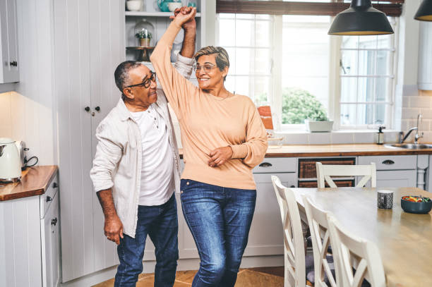 снимок пожилой пары, танцующей на кухне - senior adult mature adult senior couple heterosexual couple стоковые фото и изображения