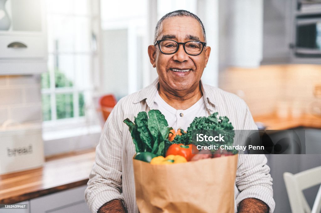 Shot of a elderly man holding a grocery bag in the kitchen Let food be thy medicine Healthy Eating Stock Photo