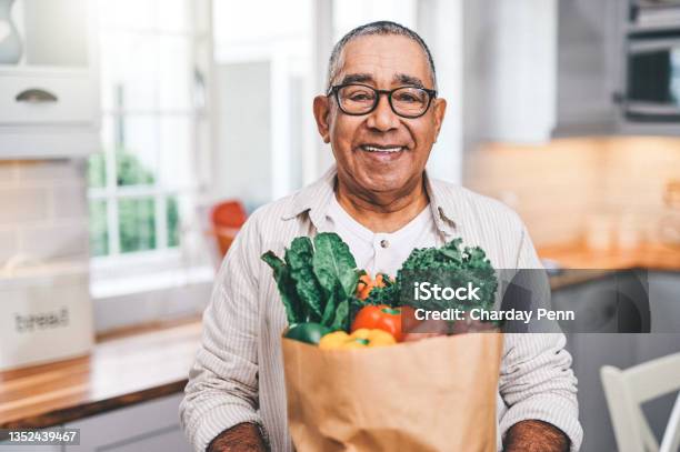 Shot Of A Elderly Man Holding A Grocery Bag In The Kitchen Stock Photo - Download Image Now