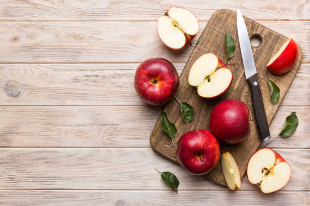 istock Fresh red apples with green leaves on table. cutting board with knife. Top view 1352439723
