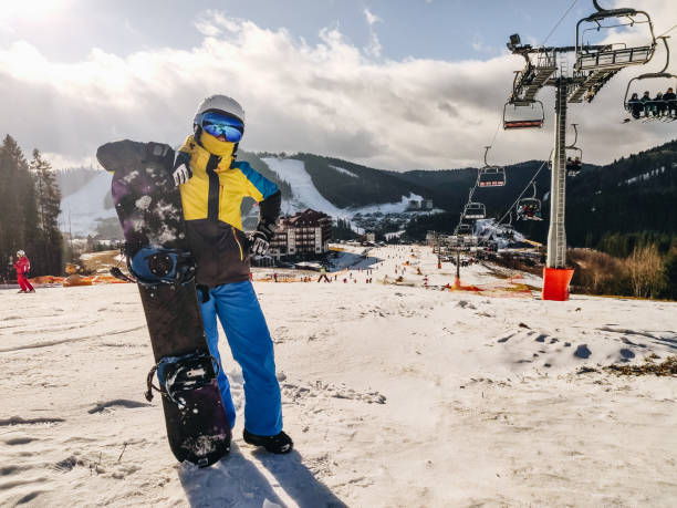 istock woman standing at ski resort hill with snowboard 1352445458