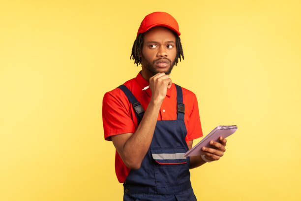istock Handyman standing with paper notebook in hands, writing down orders, having thoughtful expression. 1352445803