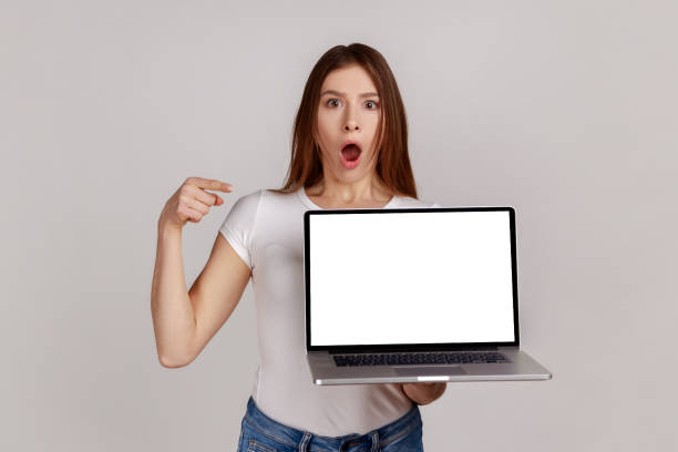 istock Woman with dark hair pointing at empty display of portable computer, copy space for advertisement. 1352446192