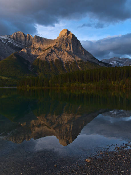 Stunning view of majestic mountain Ha Ling Peak in the Rocky Mountains near Canmore, Alberta, Canada after sunrise mirrored in the smooth water of Rundle Forebay reservior. stock photo