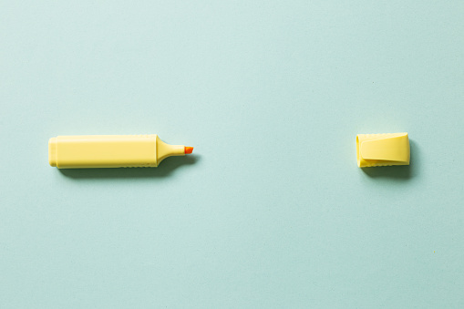 Yellow highlighter pen isolated on blue background. top view, copy space
