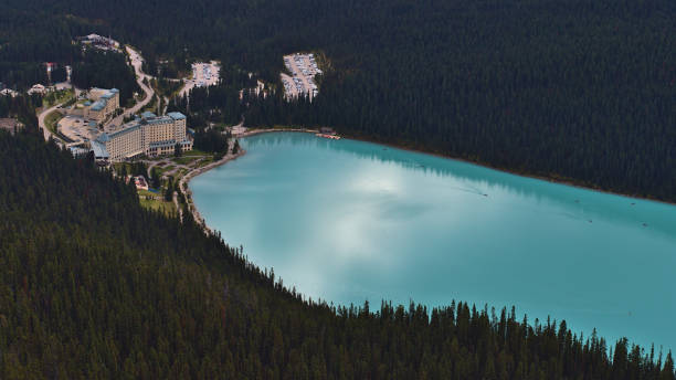 Aerial view of Lake Louise with turquoise colored water surrounded by forests in Banff National Park, Alberta, Canada in the Rocky Mountains with famous hotel and parking in autumn. stock photo