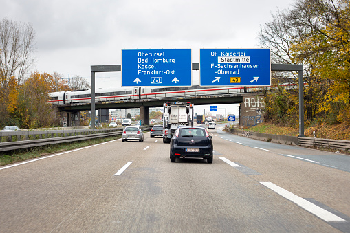 Frankfurt, Germany - November 08, 2021: Road signs over German highway A661 nearby Offenbach. Some road users in the foreground. Bundesautobahn 661 (BAB 661 or A 661) is an Autobahn in Germany - it starts in Oberursel and goes along Frankfurt am Main and Offenbach am Main to its ending in Egelsbach.