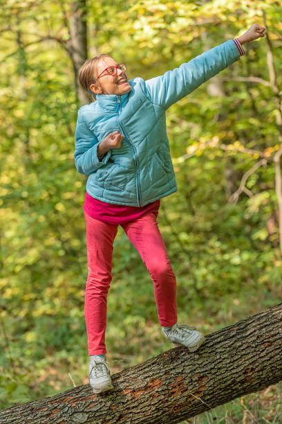 istock Young Girl standing on Fallen Down Tree Trunk and Catching Balance 1352451507