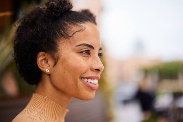 Smiling young woman with freckles standing outside in summer stock photo
