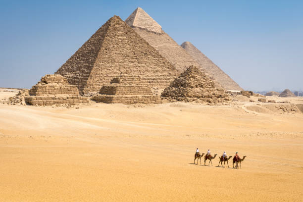 panoramic view of giza pyramid complex with camel caravan , egypt - ancient world imagens e fotografias de stock