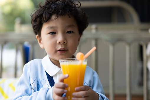 A little boy who drinks juice in a restaurant