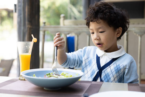 istock A little boy eating salad in a restaurant 1352457524