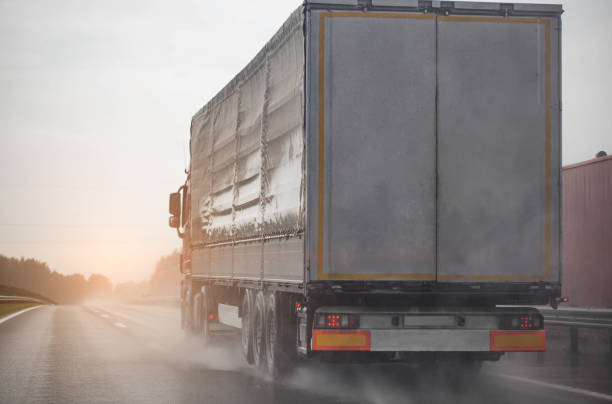 A semi-trailer truck drives on a wet road during poor visibility and rain. Bad foggy and rainy weather. Copy space for text A semi-trailer truck drives on a wet road during poor visibility and rain. Bad foggy and rainy weather truck rain stock pictures, royalty-free photos & images