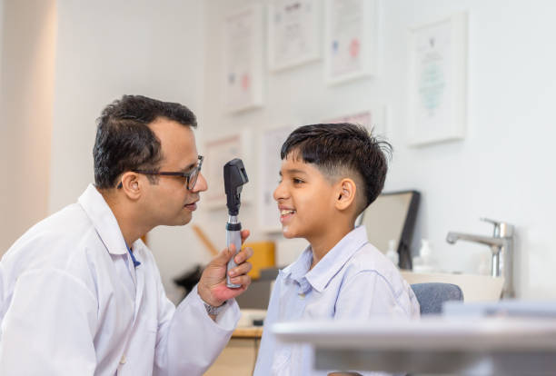 istock Boy doing eye test checking examination with optometrist in optical shop, Smiling Indian-thai boy choosing glasses in optics store 1352461341