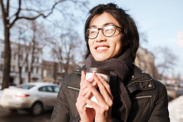 istock Cheerful young asian man drinking coffee. 1352462561