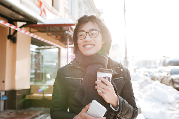 istock Young asian man drinking coffee and holding phone. 1352462936