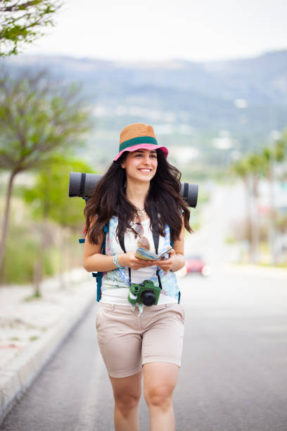 istock Cheerful young woman with backpack walking along asphalt road. 1352464796