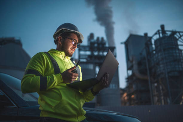 Concentrated engineer working with laptop during night shift in gas and oil industry station. stock photo