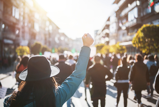 Young woman with a raised fist protesting in the street
