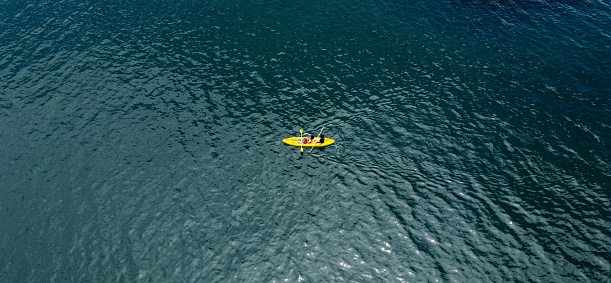 Drone view of couple using kayak during recreation time during vacation.