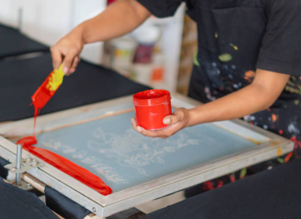screen printing workers wearing masks are working on their workshop order t-shirts
