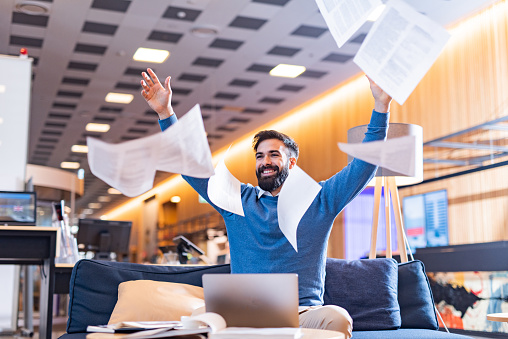 Happy man throw away papers celebrating success at work