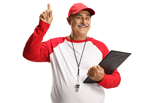Mature baseball coach with a wistle and a clipboard pointing up isolated on white background