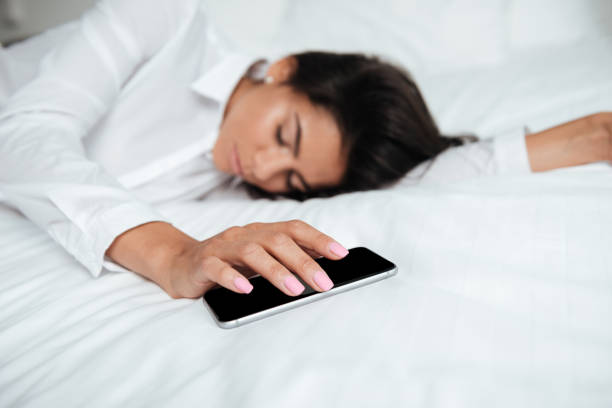 istock Woman with mobile phone in hand on bed 1352473180