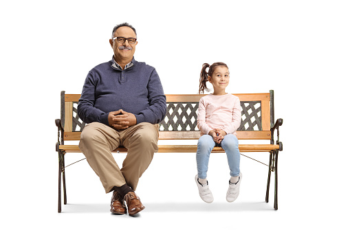 Mature man and a little girl sitting on a bench and looking at camera isolated on white background