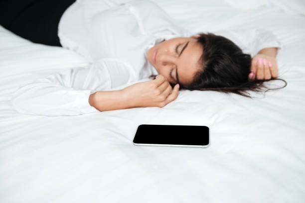 istock Woman sleeping on bed withmobile phone after hard working day 1352473359