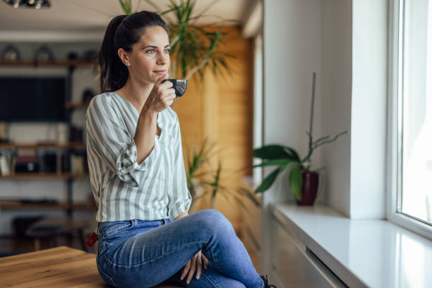 istock Tranquil adult woman, relaxing at home, drinking 1352473511