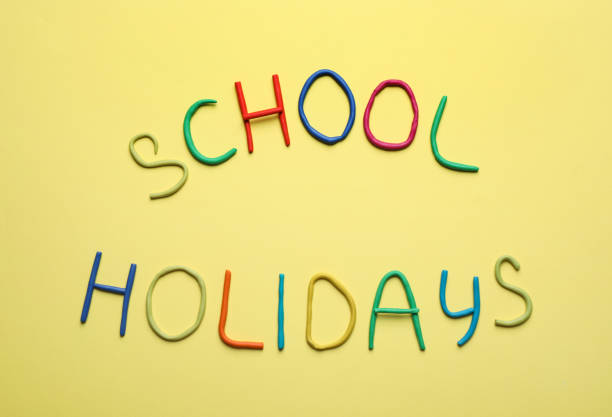 istock Text School Holidays made of modelling clay on yellow background, flat lay 1352473741